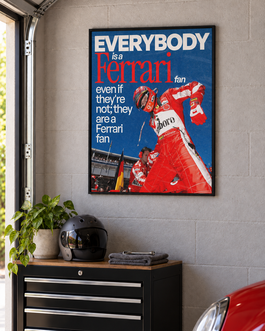 Everybody Is a Ferrari Fan – F1 poster v čiernom ráme na stene garáže
